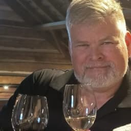 Robb, who writes Niagara Winery Weekly, in a timber-framed winery tasting room with a glass of red in front of him